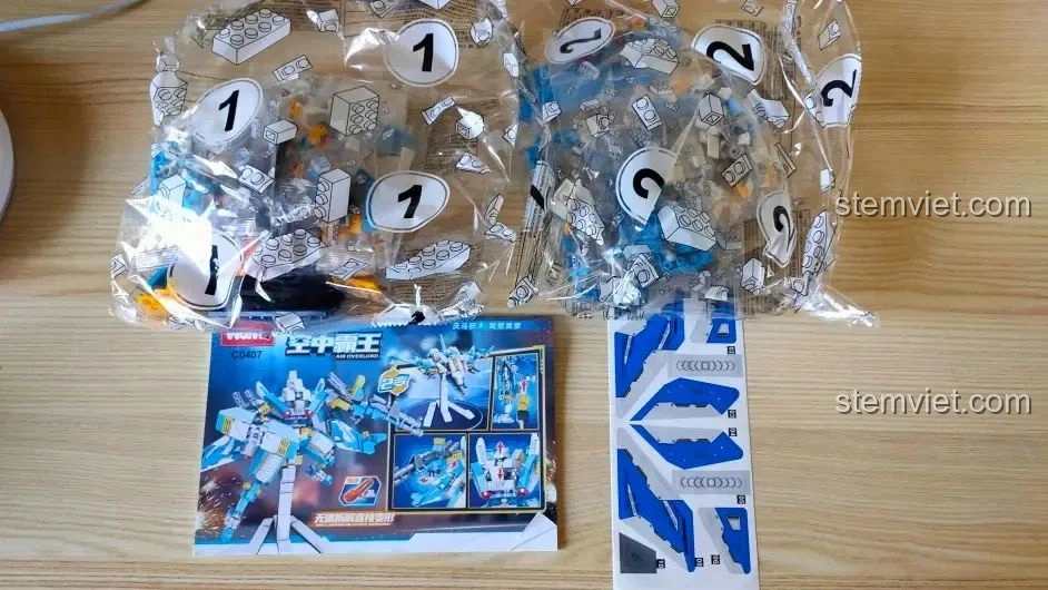 Toàn bộ phụ kiện bên trong hộp đồ chơi WOMA C0407: các túi mảnh ghép được đánh số, sách hướng dẫn chi tiết và bộ sticker trang trí.