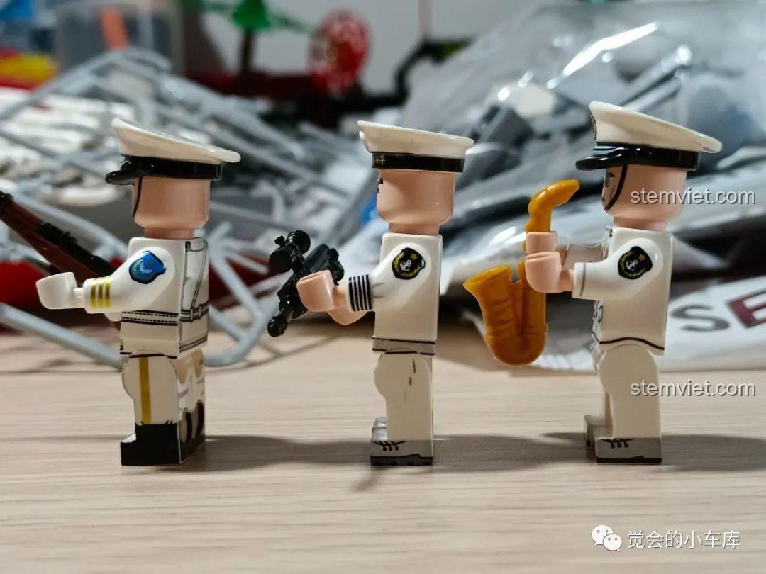 Góc nhìn bên hông của các minifigures, tập trung vào các phụ kiện độc đáo như súng trường, súng ngắn và kèn saxophone vàng óng.