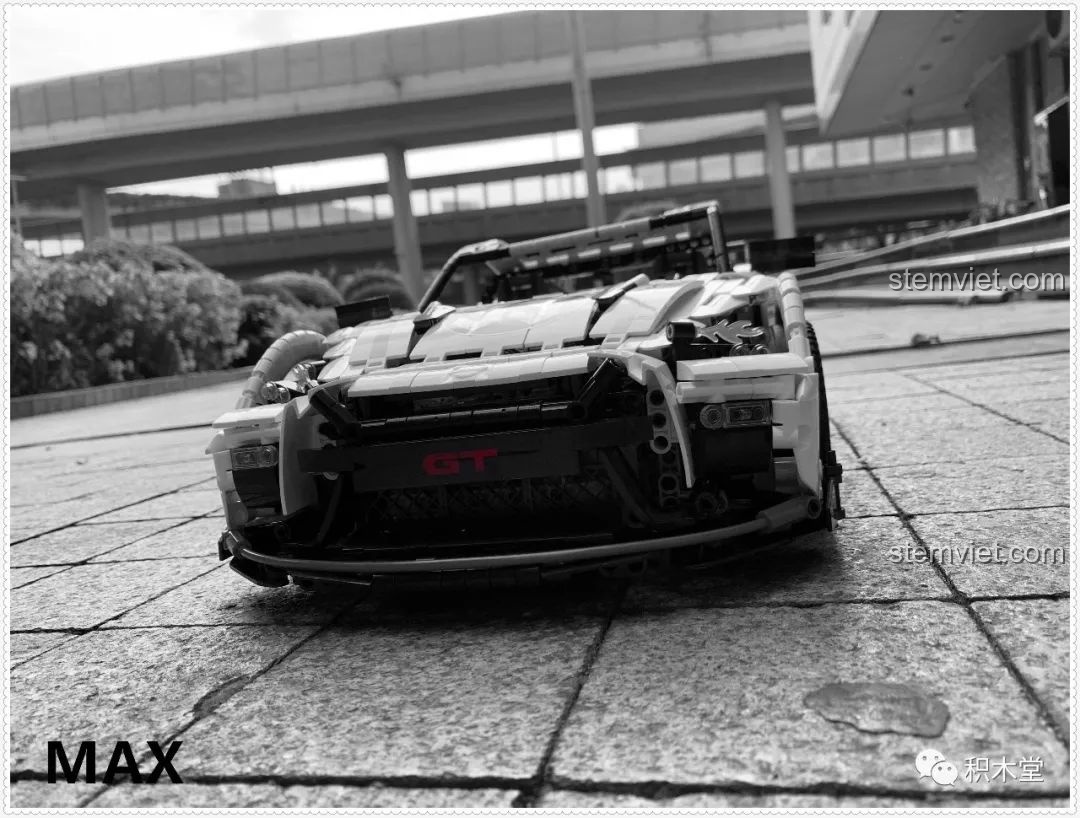 Mô hình lắp ráp Qizhile 23010 Nissan GT-R với hiệu ứng ảnh đen trắng, chụp từ góc thấp phía trước, tạo cảm giác nghệ thuật.