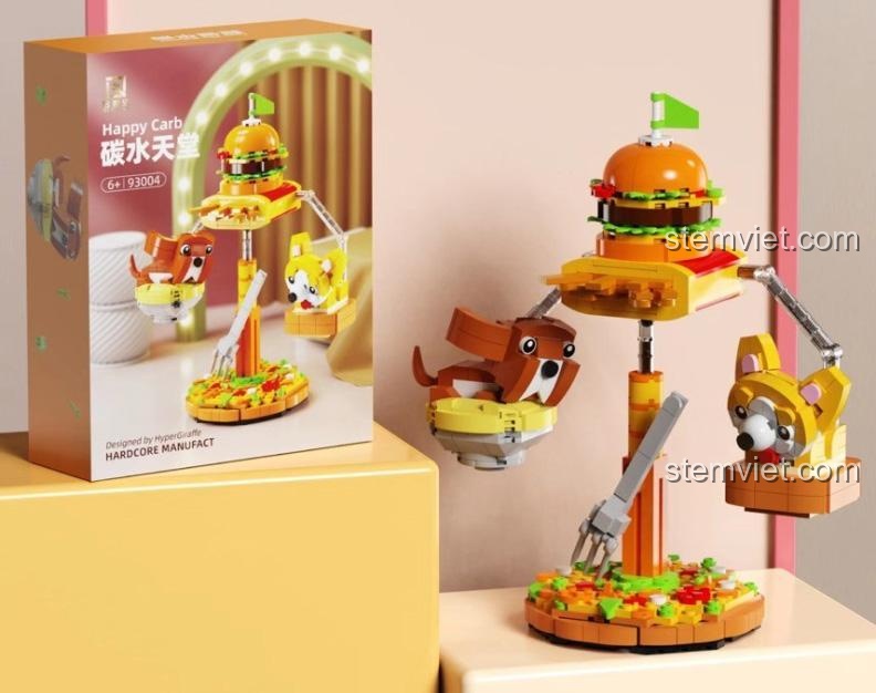 Hộp sản phẩm bộ đồ chơi Happy Carb 93004 của hãng 启智乐, mô tả hai chú chó Corgi và chó nâu đang chơi đùa quanh chiếc bánh burger khổng lồ, phù hợp cho bé 6+ tuổi