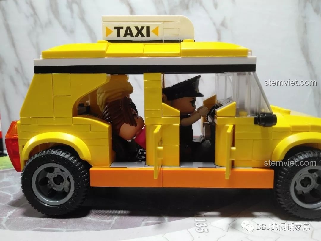 Góc nhìn bên hông xe taxi QMAN 1134 với các minifigures ngồi bên trong và cửa xe mở.