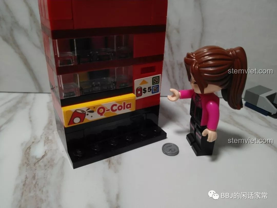Minifigure nữ đang cố gắng sử dụng đồng xu với máy bán nước, một chi tiết hài hước trong bộ QMAN 1134.