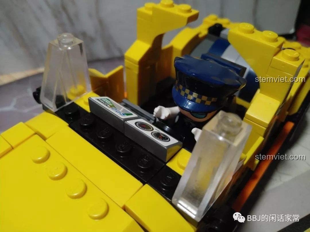 Minifigure tài xế ngồi bên trong xe taxi đang lắp ráp, cho thấy nội thất xe khá đơn giản.