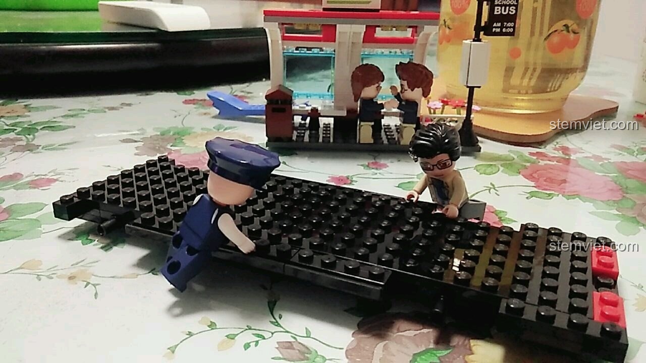 Một cậu bé học sinh đi xe đạp đến trạm chờ xe buýt, một kịch bản chơi sáng tạo với bộ lắp ráp Xe buýt trường học QMAN.