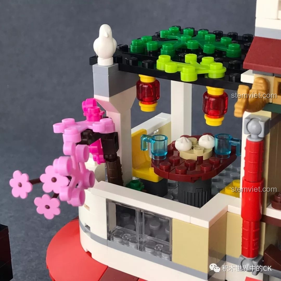 Khu vực ngồi uống trà bán lộ thiên trên tầng hai của nhà hàng QMAN 1137, trang trí với hoa mai và đèn lồng.