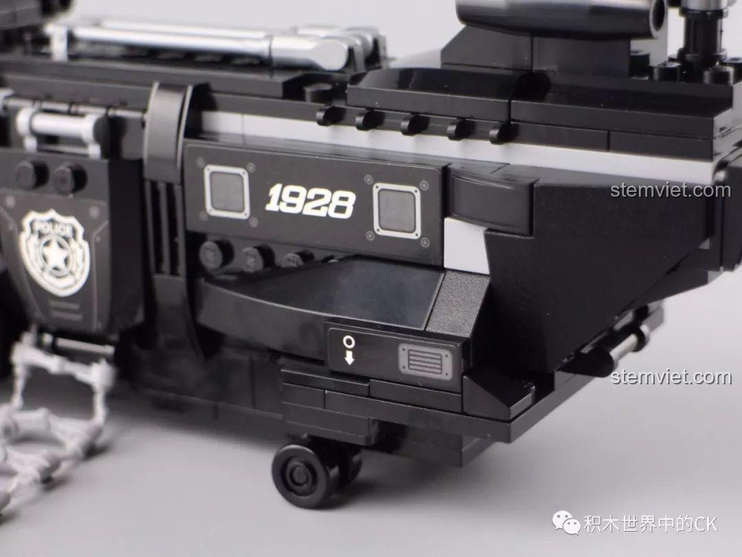 Minifigure cảnh sát đu thang dây từ cửa hông đang mở của trực thăng Qman 1928.