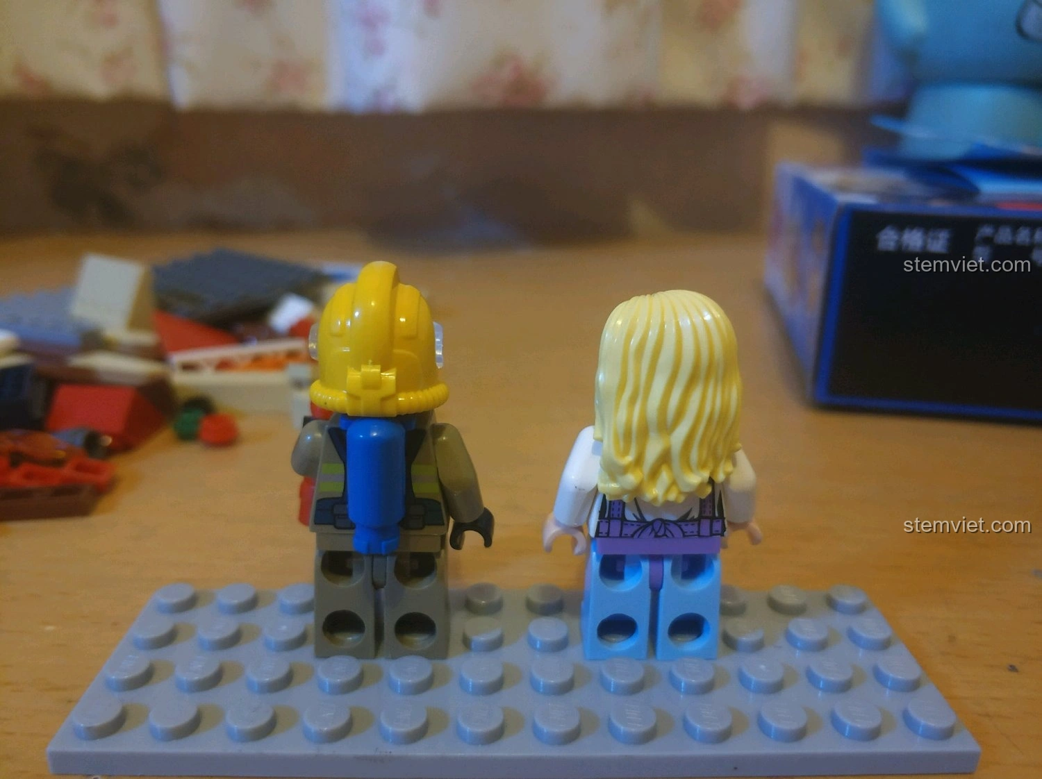 Mặt sau của hai minifigures lính cứu hỏa và nhân viên nhà sách từ bộ QMAN 2804, thể hiện chi tiết trang phục.