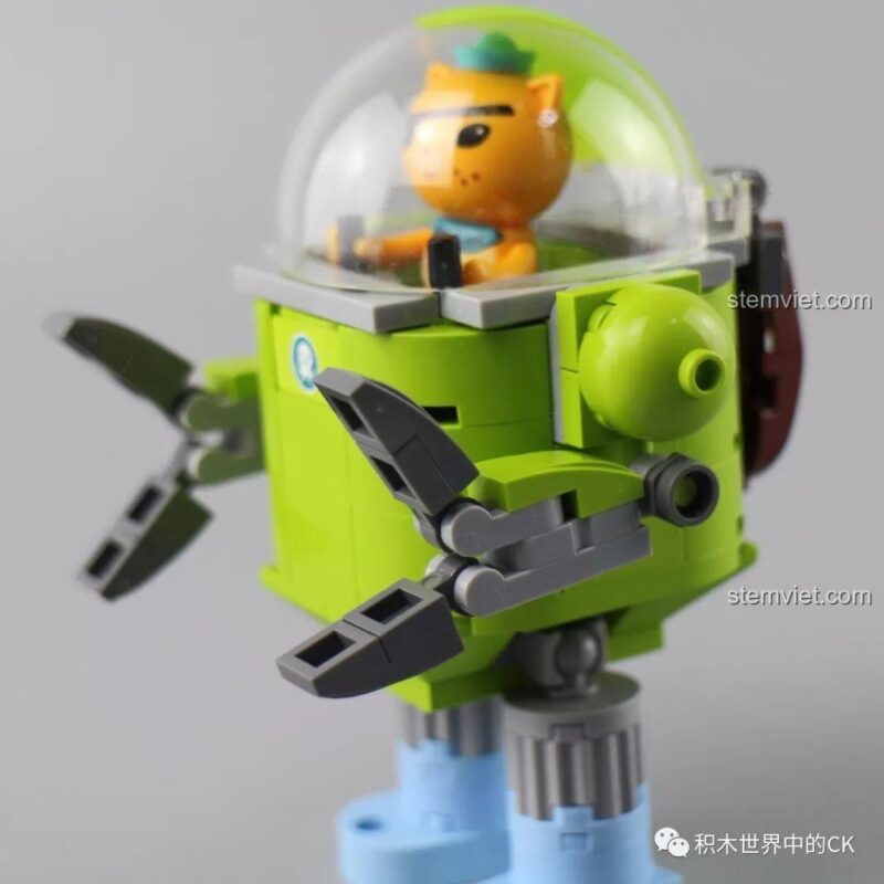 Nhân vật Kwazii đang điều khiển robot cứu hộ mini màu xanh lá từ bộ lắp ráp Tàu Cá Voi Xanh.