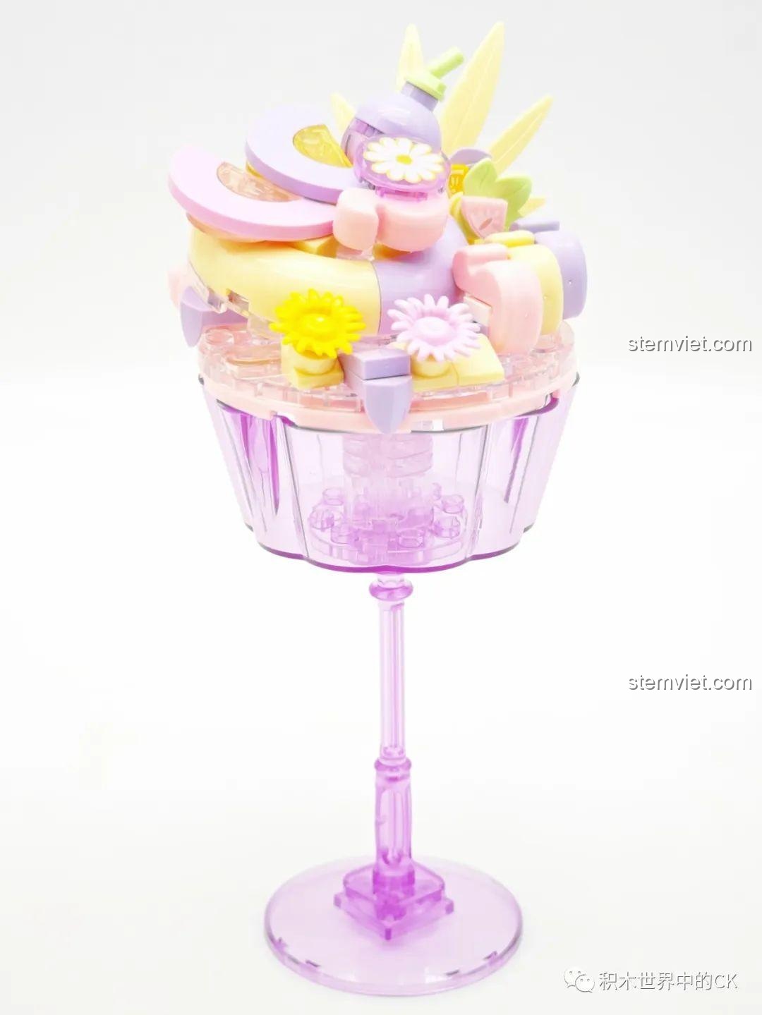 Mô hình đèn bánh pudding Sembo màu tím đã hoàn thành, với các chi tiết trang trí hình hoa và lá, đặt trên đế cốc cao.