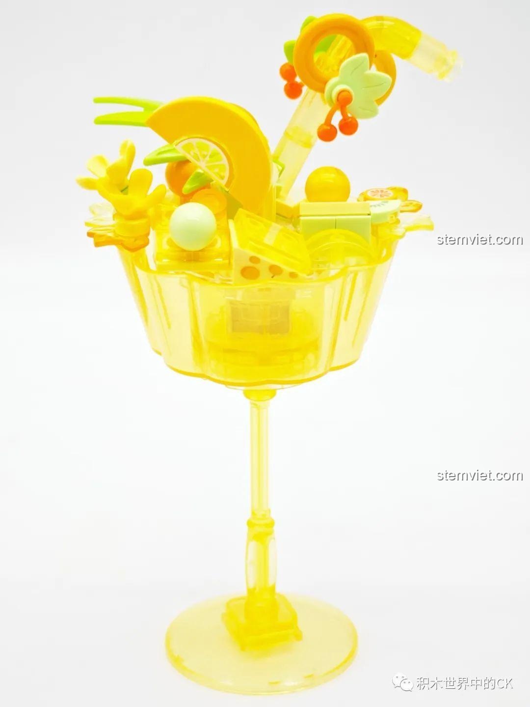 Mô hình đèn bánh pudding Sembo màu vàng đã hoàn thành, với các chi tiết trang trí hình lát chanh và hoa, đặt trên đế cốc cao.