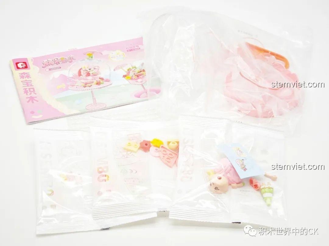 Quá trình mở hộp bộ đồ chơi lắp ráp đèn bánh pudding Sembo màu hồng, hiển thị sách hướng dẫn và các túi mảnh ghép được đóng gói cẩn thận.