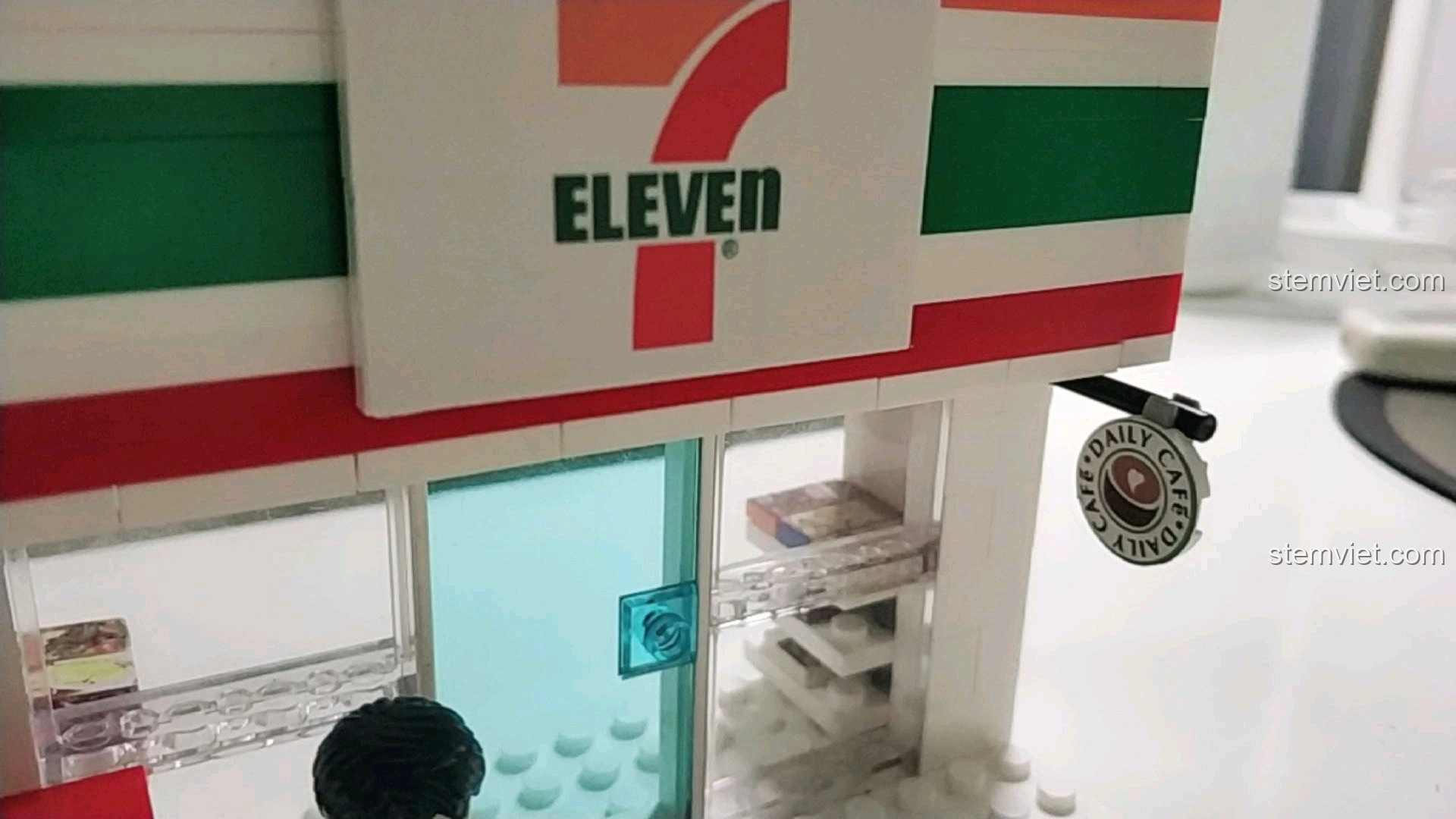 Biển hiệu 7-Eleven và cửa ra vào của mô hình cửa hàng tiện lợi, thể hiện rõ thương hiệu.