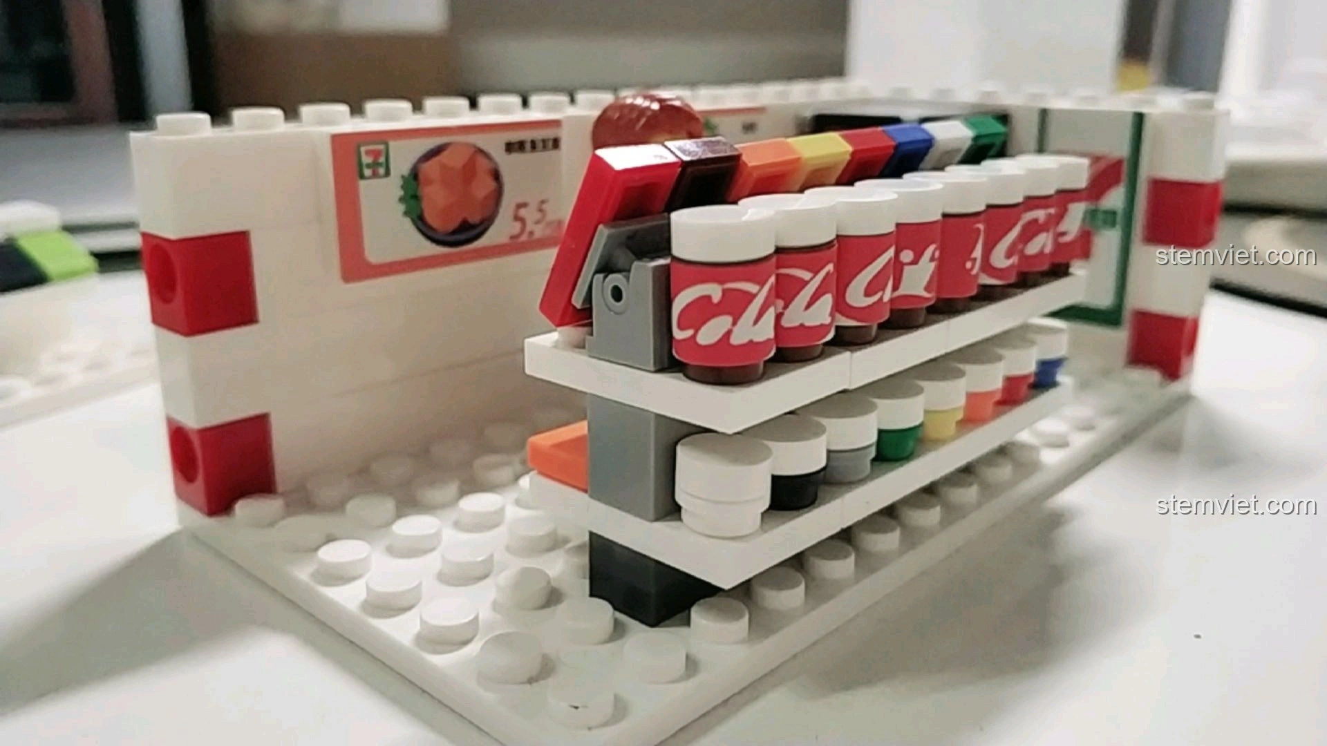 Chi tiết kệ hàng với các chai nước ngọt và sản phẩm khác trong mô hình cửa hàng tiện lợi 7-Eleven.