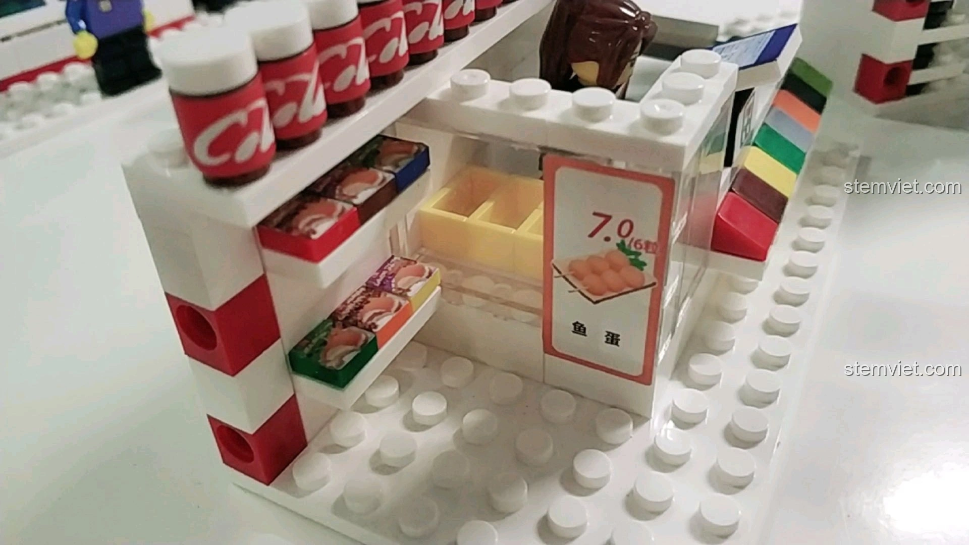 Khu vực trưng bày thực phẩm tươi sống với biển giá trong mô hình cửa hàng tiện lợi 7-Eleven.
