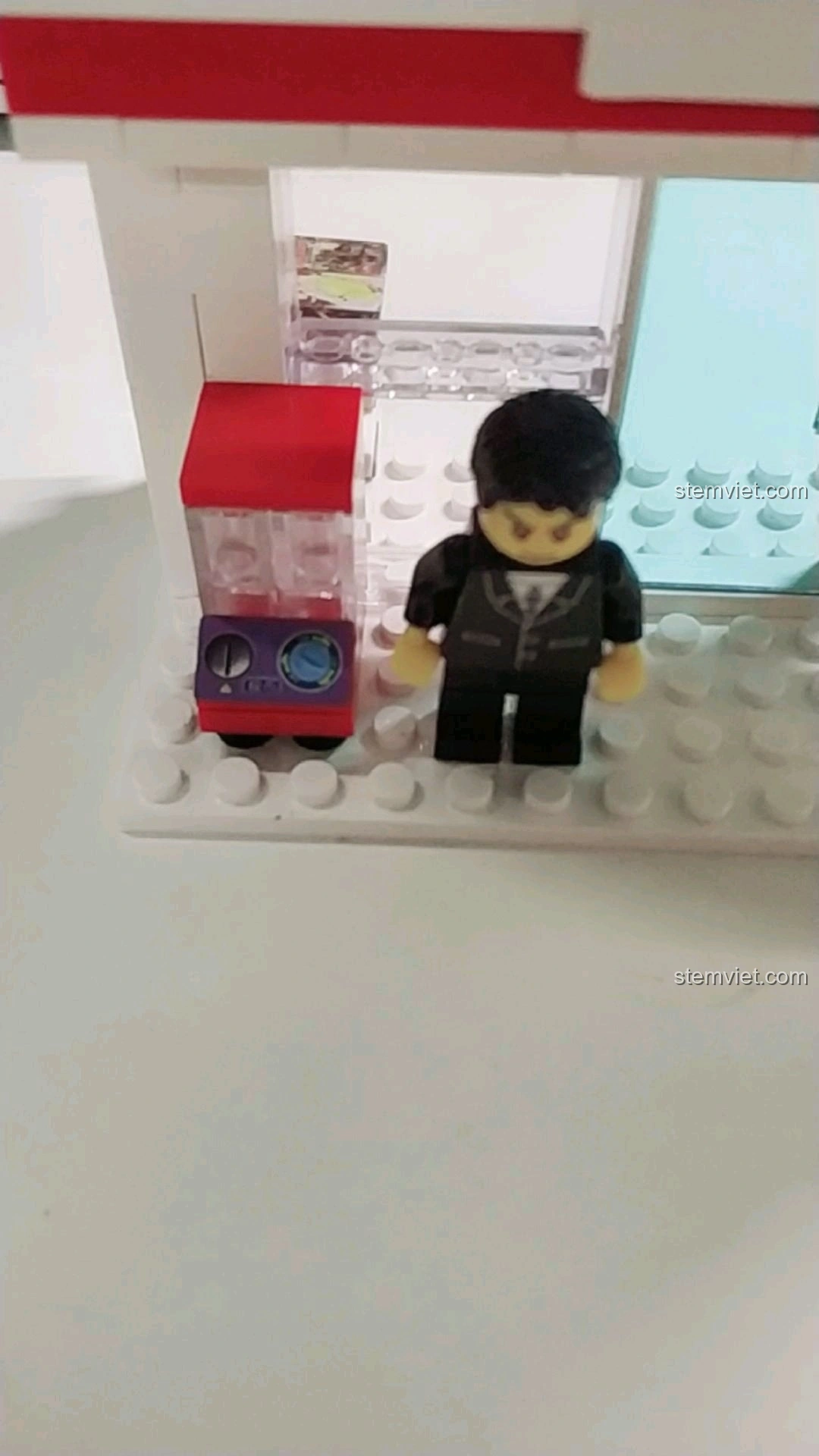 Minifigure nam đứng cạnh máy bán kẹo tự động trong mô hình cửa hàng tiện lợi 7-Eleven.