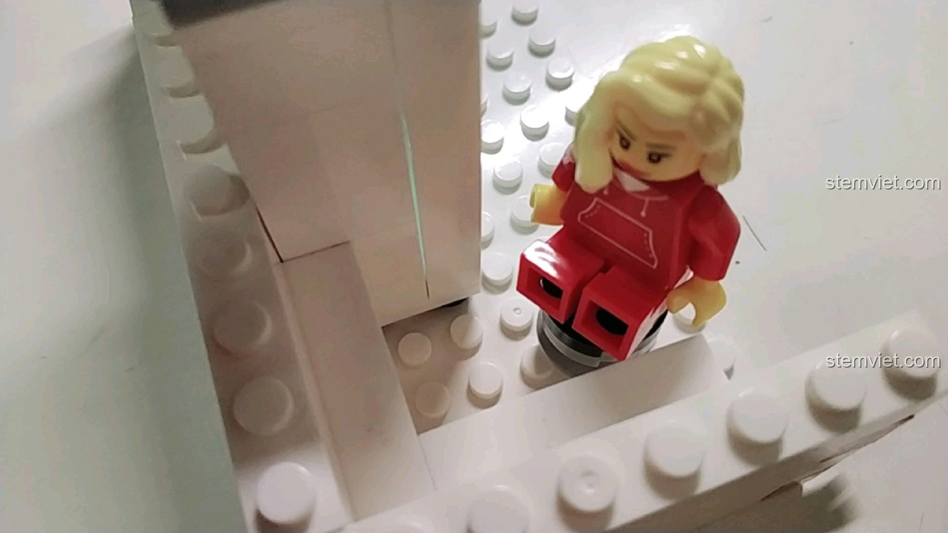 Minifigure nữ ngồi trên ghế trong mô hình cửa hàng tiện lợi 7-Eleven, thể hiện khu vực nghỉ ngơi.