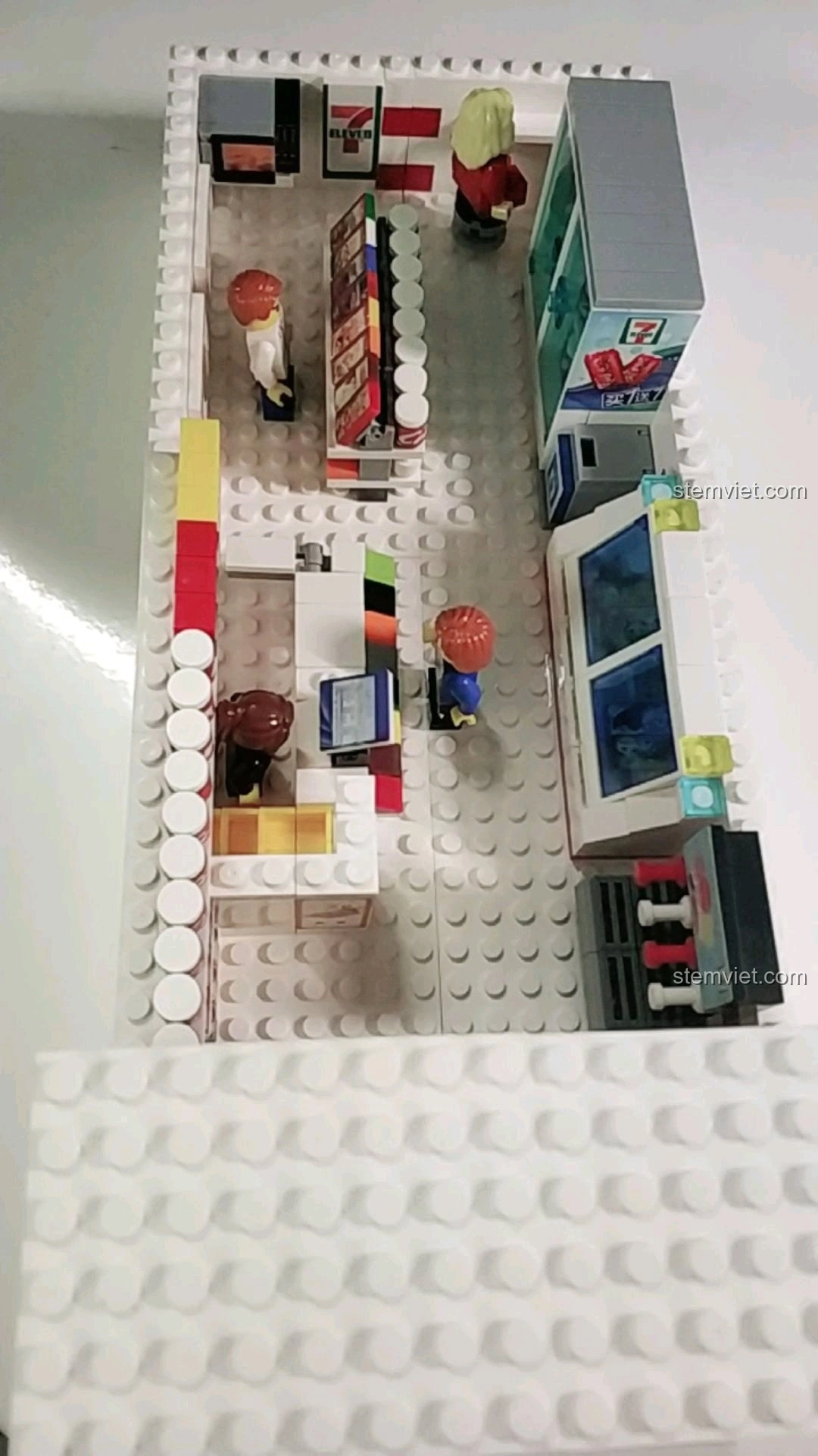 Góc nhìn từ trên cao mô tả chi tiết nội thất bên trong cửa hàng tiện lợi 7-Eleven lắp ráp, với các khu vực khác nhau.