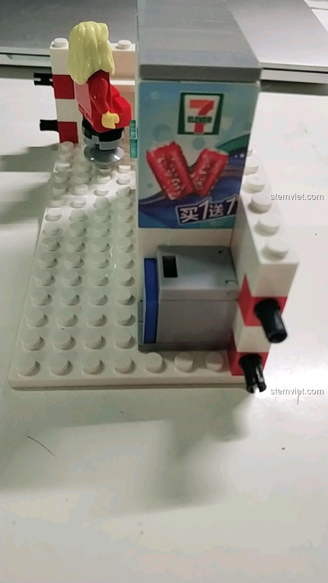 Góc nhìn bên cạnh tủ lạnh và thùng rác trong mô hình cửa hàng tiện lợi 7-Eleven.