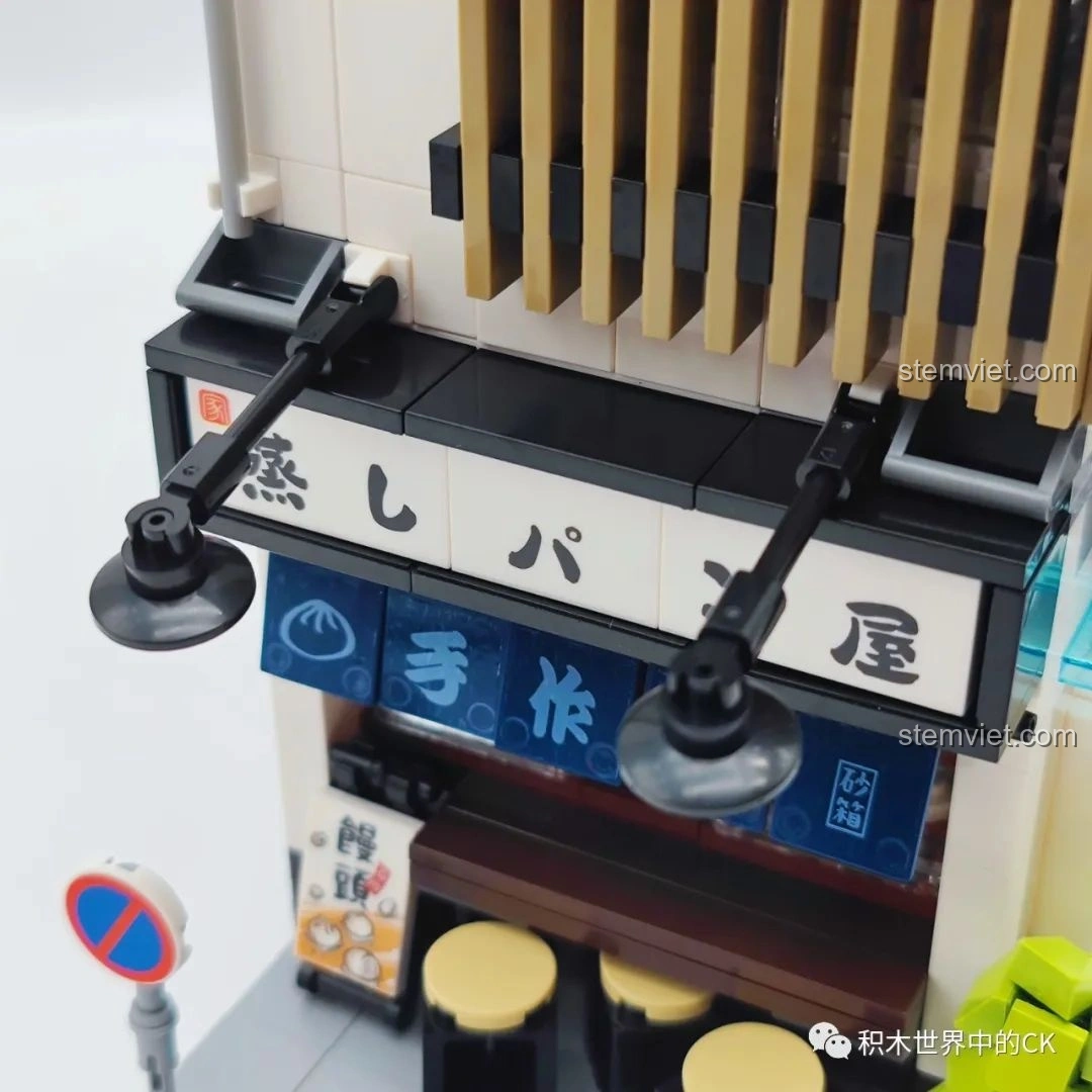 Cận cảnh máy bán hàng tự động và thùng rác bên ngoài mô hình đồ chơi CaDA C66006 Nhà Bánh Bao Nhật Bản.