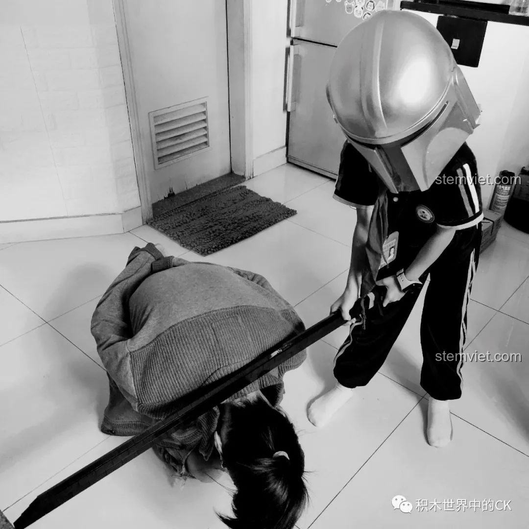 Bé trai đội mũ bảo hiểm đang chơi với mô hình Thanh kiếm Thiên Tỏa Trảm Nguyệt DK 1501, thể hiện tính giải trí.