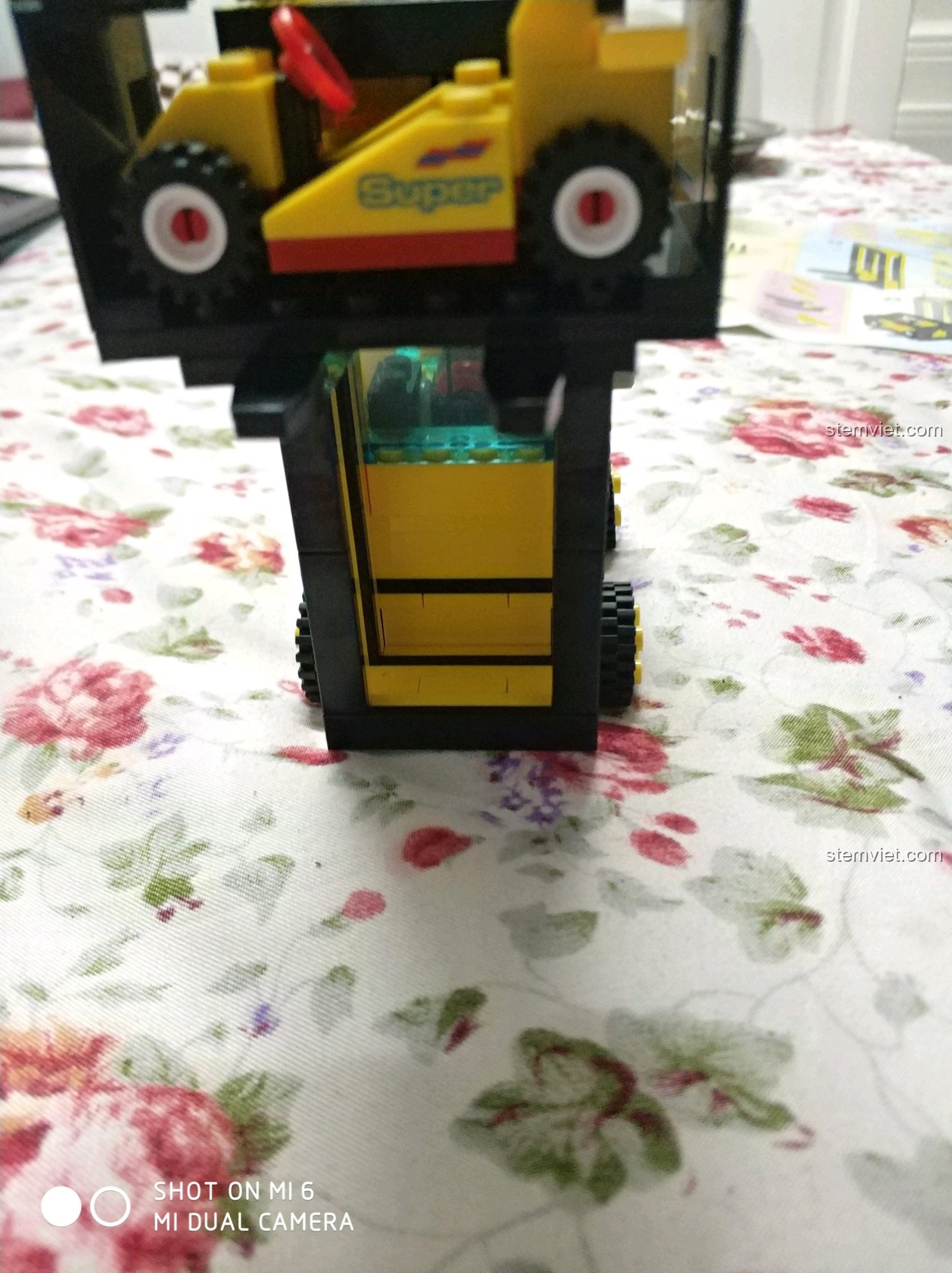 Xe nâng Enlighten 0493 Xe Nâng Hàng Lắp Ráp đang nâng xe đua mini, thể hiện khả năng vận chuyển hàng hóa.