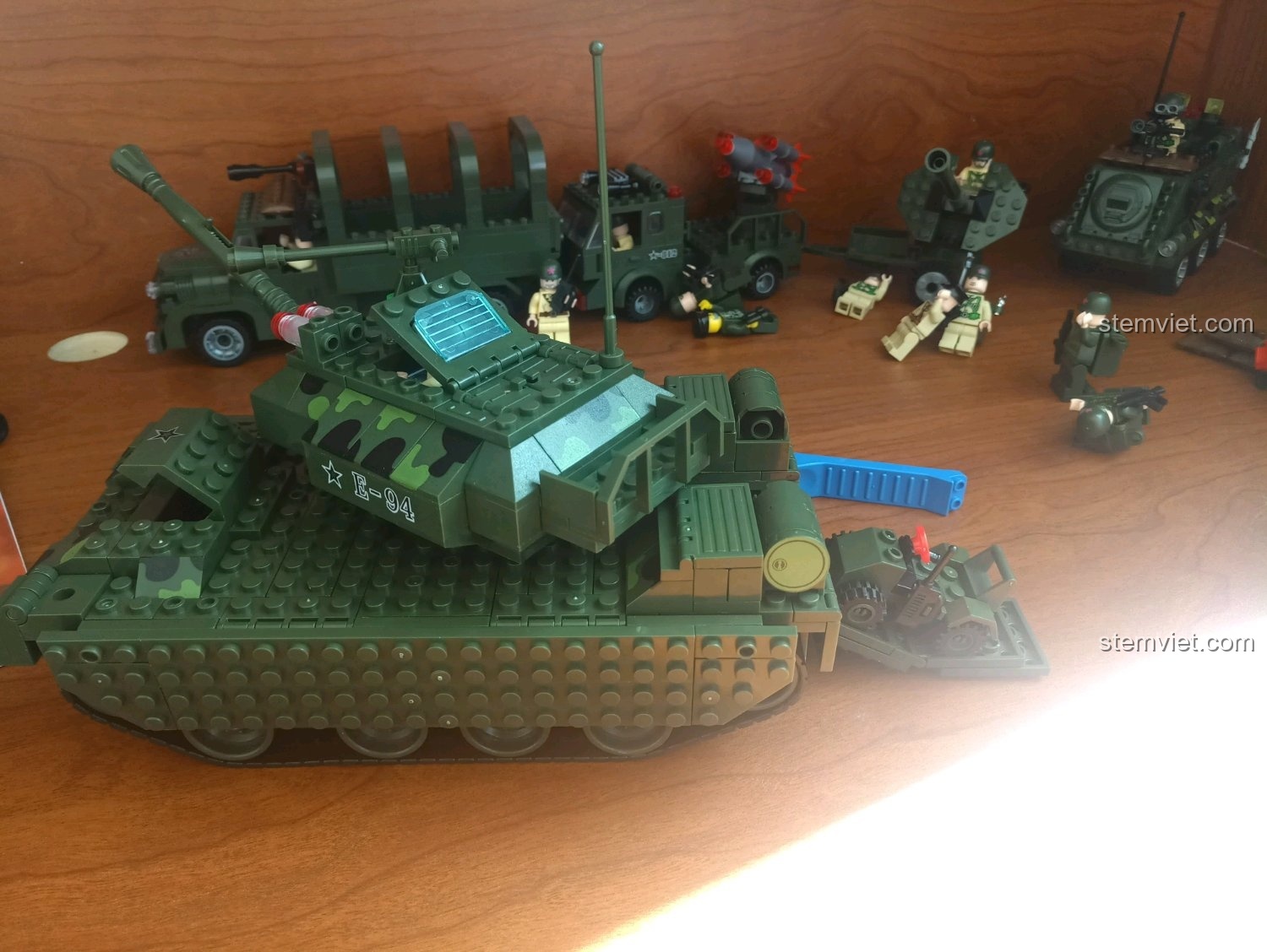 Toàn cảnh mô hình xe tăng Enlighten 0494 với các chi tiết quân sự khác ở hậu cảnh, tạo bối cảnh chiến trường.