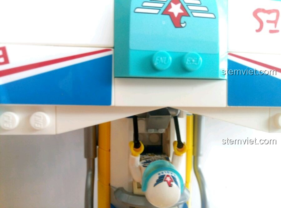 Cận cảnh phi công tí hon đang treo mình dưới thân máy bay biểu diễn hai cánh Enlighten 1125, thể hiện tính năng chơi đùa độc đáo.