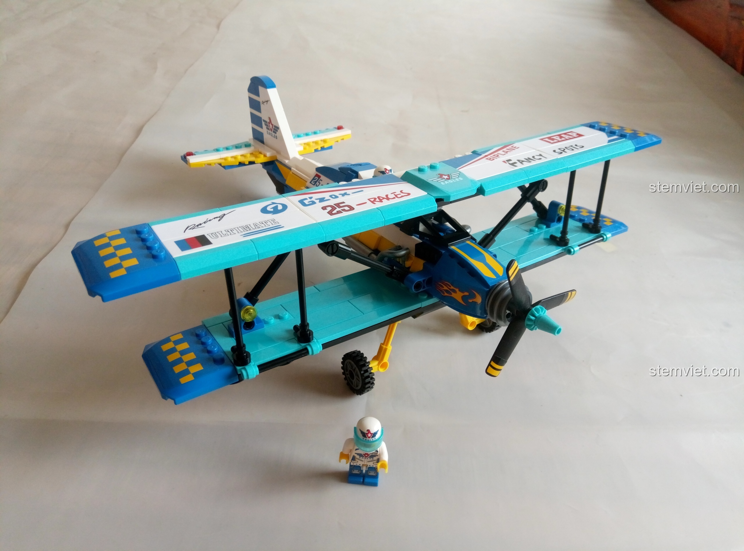 Mô hình máy bay biểu diễn hai cánh Enlighten 1125 đã hoàn thành, màu xanh dương và vàng nổi bật, cùng phi công tí hon.