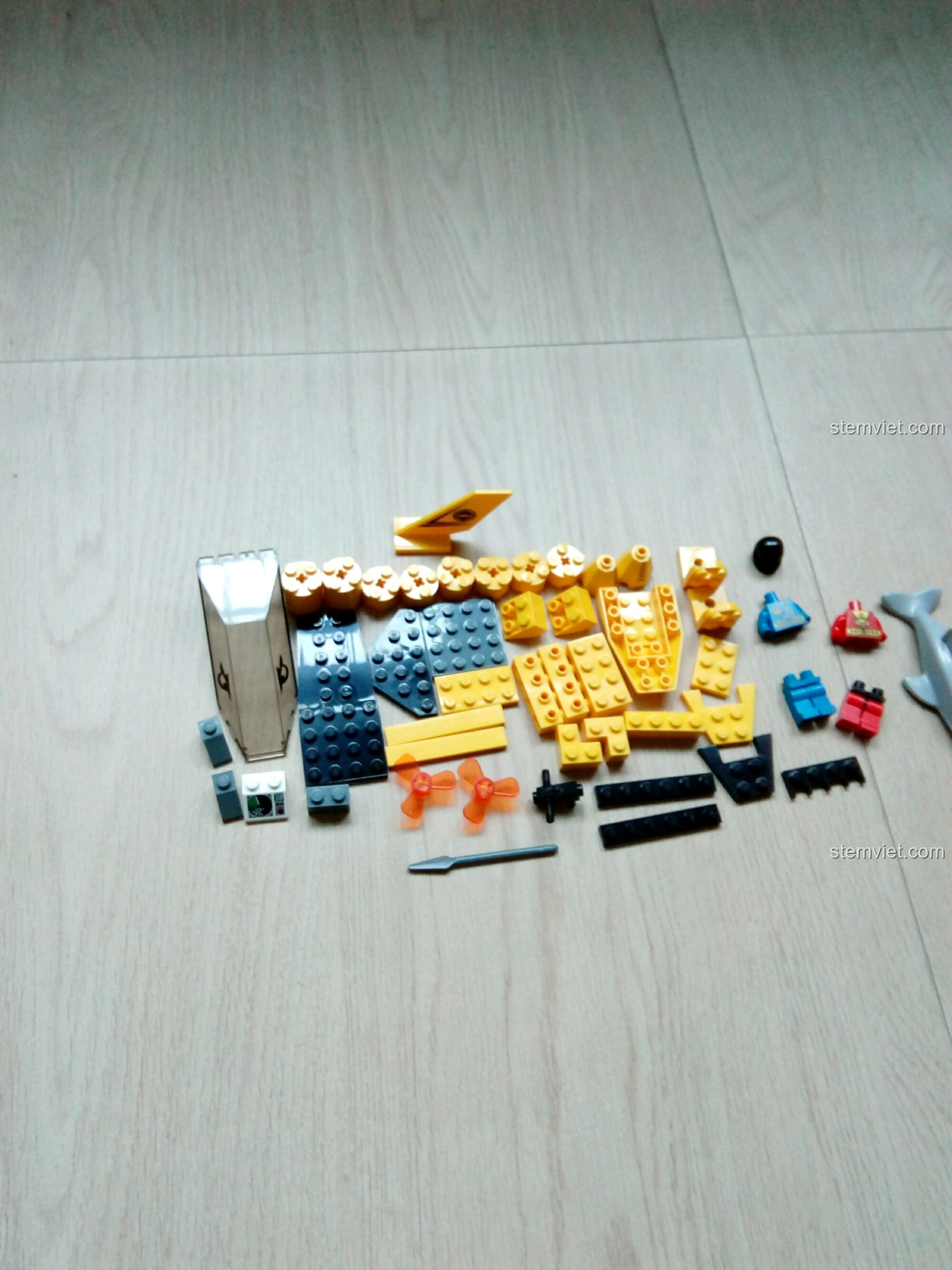 Toàn bộ linh kiện màu vàng và đen của bộ lắp ráp Tàu Ngầm Quan Sát Cá Heo Enlighten 1215 được trải ra trên sàn gỗ. Trải nghiệm QMAN 1215 Tàu ngầm thám hiểm đại dương.