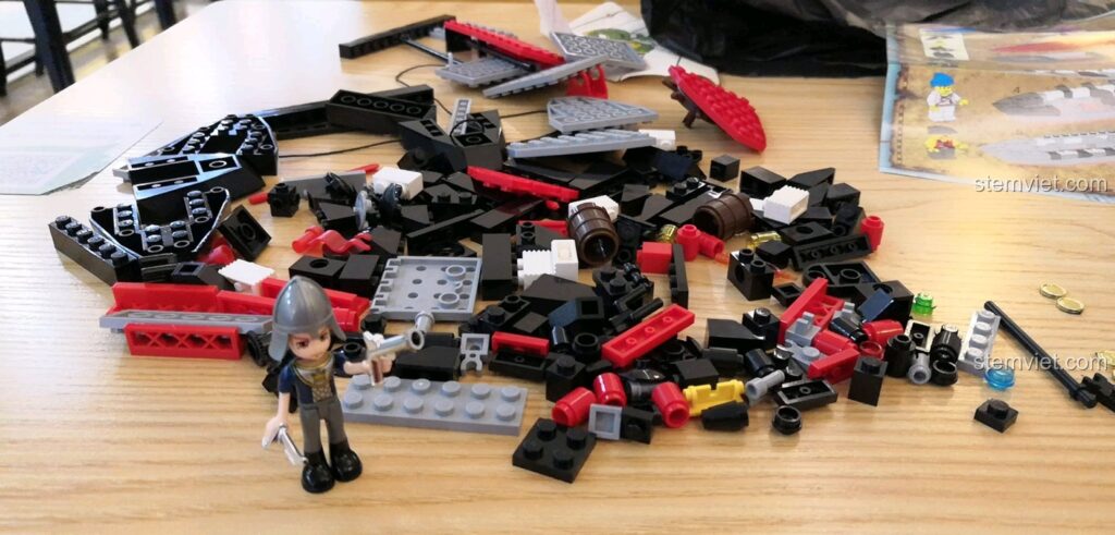 Các mảnh ghép Tàu Hải Tặc Barbara 301 của Enlighten được bày ra trên bàn gỗ, sẵn sàng cho việc lắp ráp.