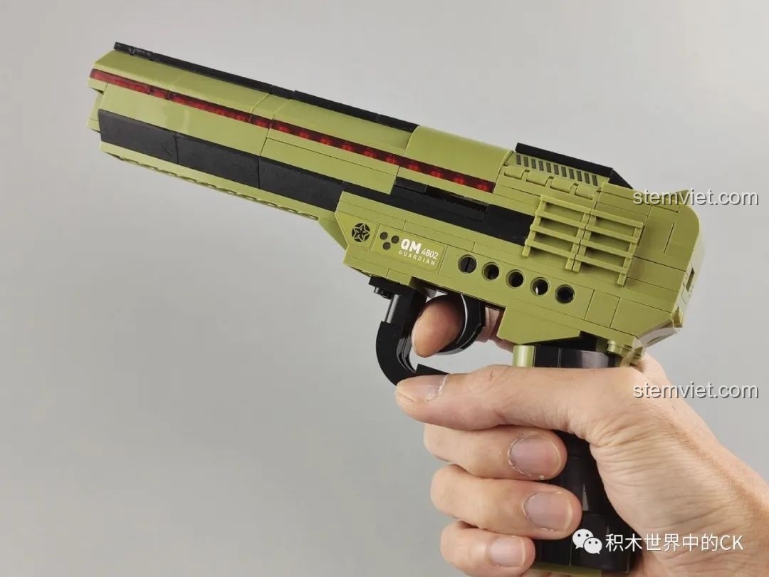 Bàn tay đang cầm mô hình súng lục lắp ráp Enlighten 4802, thể hiện kích thước và cảm giác cầm nắm.