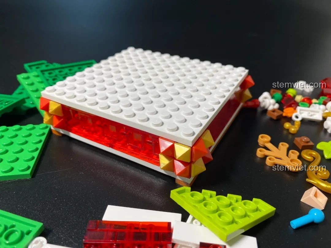 Quá trình lắp ráp phần đế của đồ chơi JAKI JK5111 Cây Thông Giáng Sinh, tạo thành hộp đựng tiện lợi.