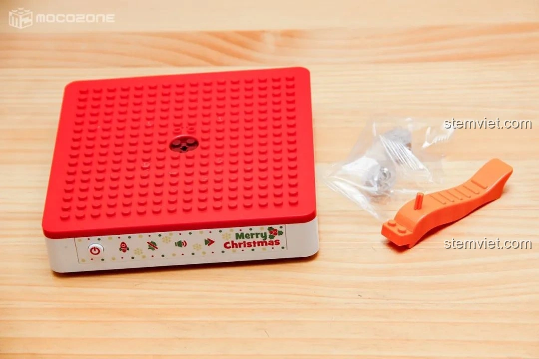 Đế nhạc màu đỏ trắng của Hộp nhạc Giáng Sinh Xoay Tự Động JAKI JK1365, có nút điều khiển cảm ứng và hai viên gạch phát sáng đi kèm.