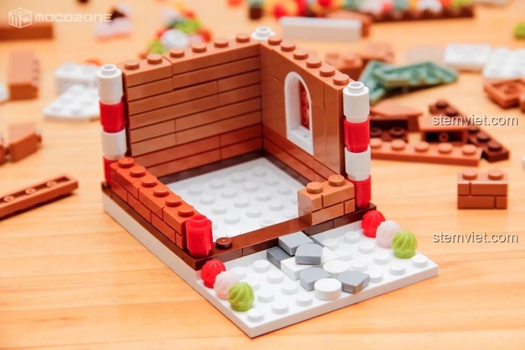 Các bức tường của ngôi nhà bánh gừng đang được xây dựng, với các chi tiết cột kẹo và cửa sổ.