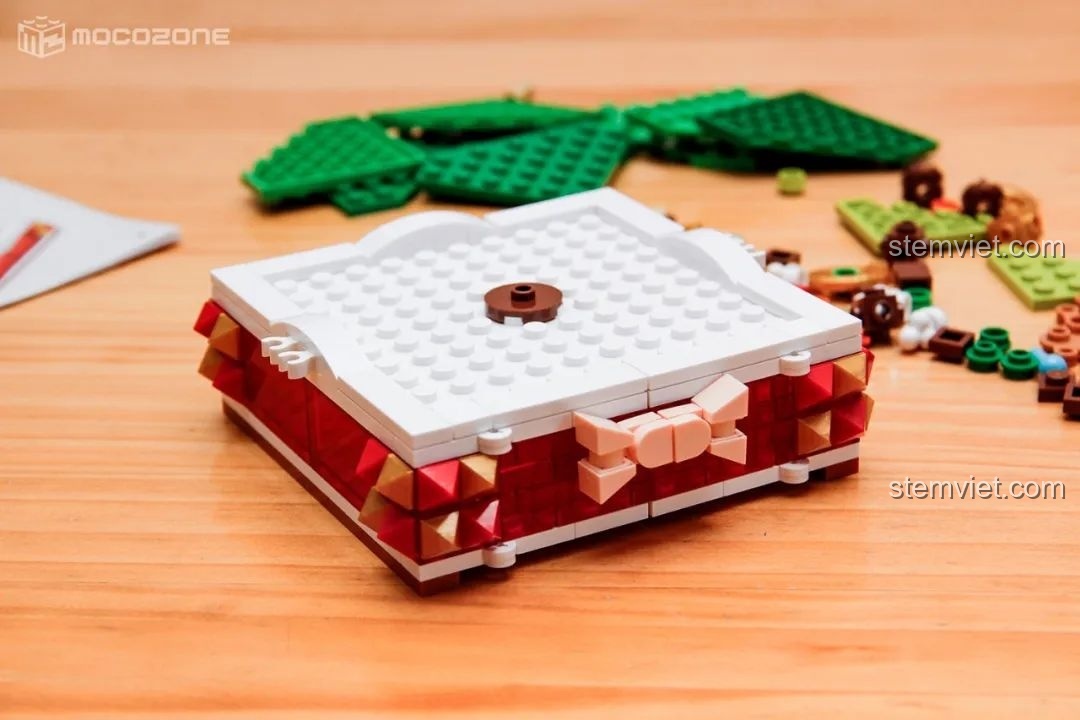 Phần đế của giá treo trang sức cây thông Noel đang được lắp ráp, với các mảnh ghép màu đỏ và trắng.