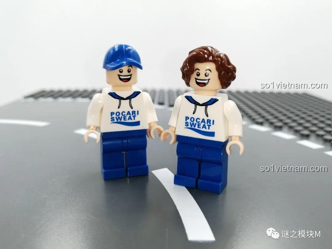 Hai minifigure Pocari Sweat, một đội mũ lưỡi trai và một tóc xoăn, đứng cạnh nhau trên nền gạch lắp ráp.