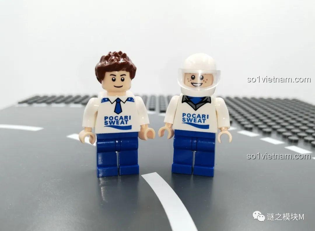 Hai minifigure Pocari Sweat, một tóc nâu và một đội mũ bảo hiểm phi hành gia, đứng trên nền gạch lắp ráp.