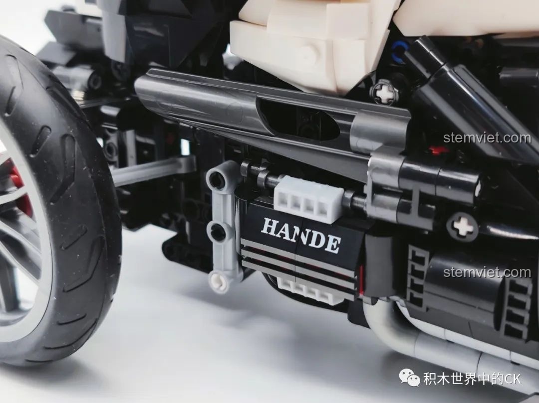 Cận cảnh phần động cơ và ống xả của mô hình JIESTAR 91024 Mô Tô Ba Bánh Honda Neo Wing RC, với các chi tiết được mô phỏng chân thực. Đây là đồ chơi lắp ráp xe mô tô điều khiển từ xa.