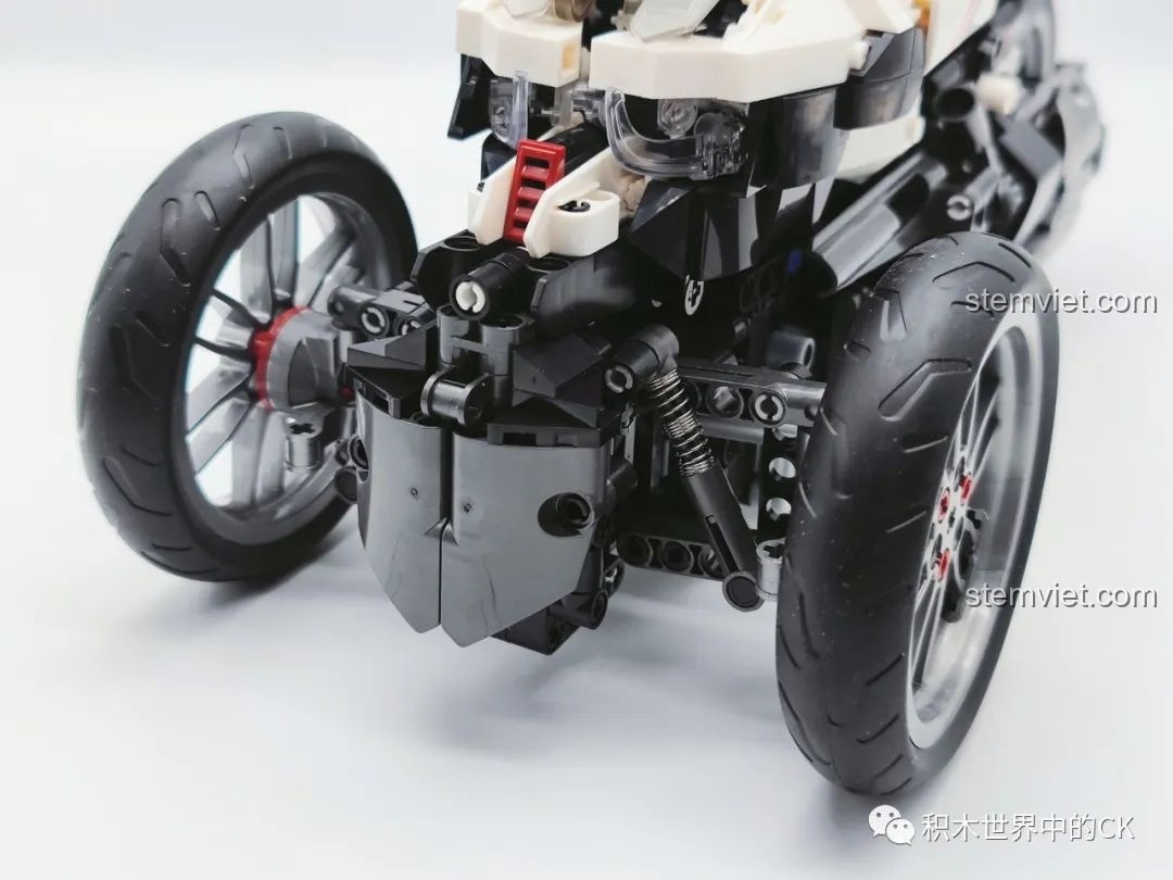 Cận cảnh hệ thống giảm xóc phía trước và bánh xe của mô hình JIESTAR 91024 Mô Tô Ba Bánh Honda Neo Wing RC, cho thấy sự tinh xảo. Đây là đồ chơi lắp ráp xe mô tô điều khiển từ xa.