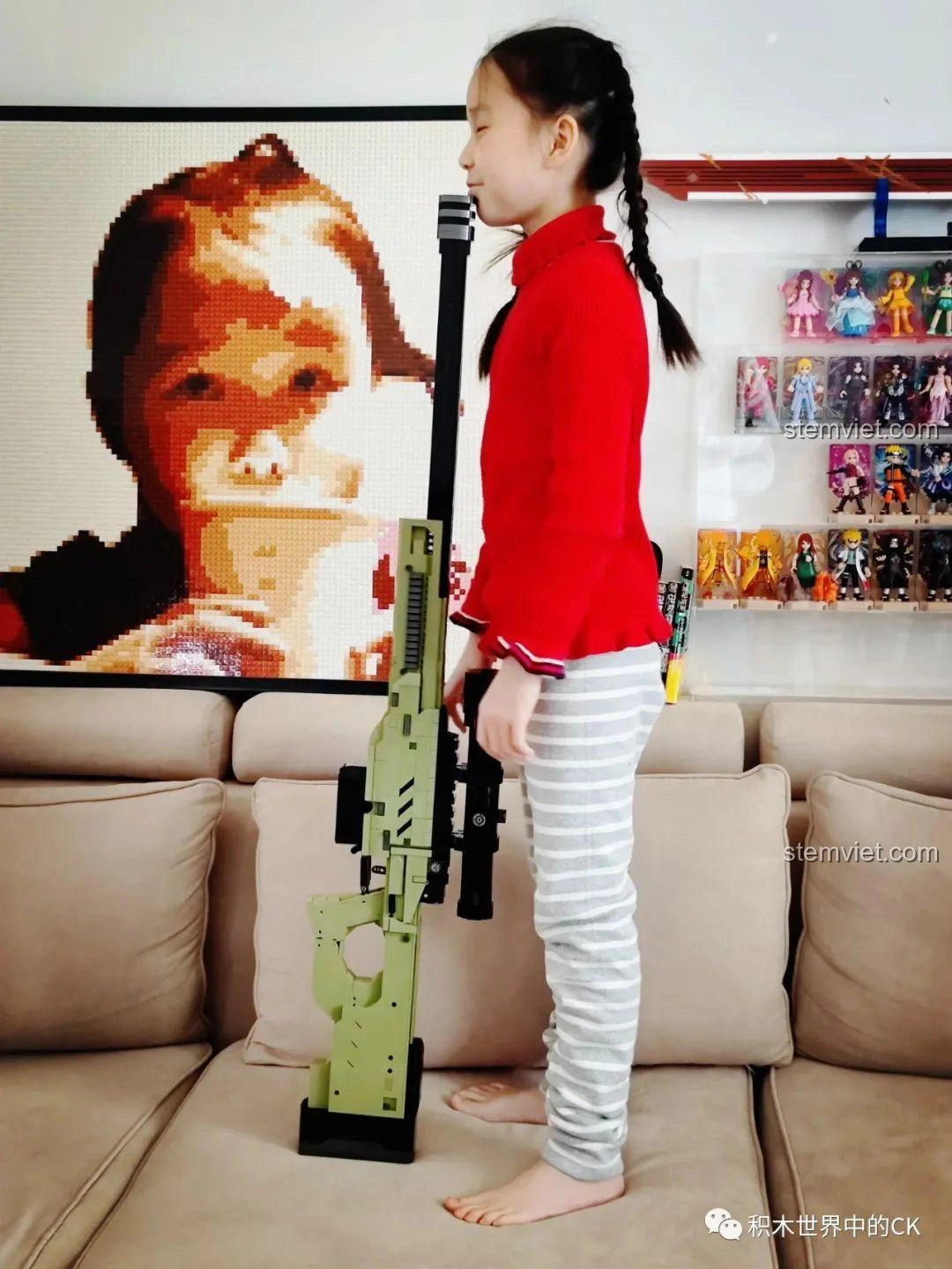 Bé gái tạo dáng vui vẻ với mô hình súng bắn tỉa AWP JIESTAR 58022, thể hiện sự thích thú khi chơi.
