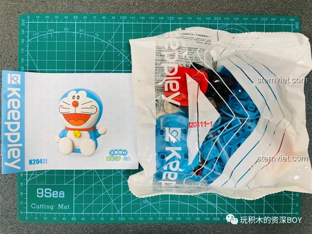 Mô hình Doraemon cổ điển K20411 đã hoàn thiện, ngồi trên thảm cắt, với nụ cười tươi tắn và dáng ngồi tròn trĩnh.
