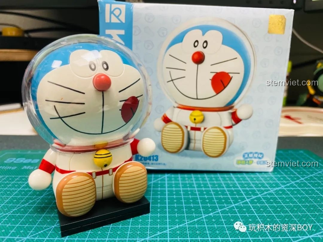 Hộp đồ chơi lắp ráp Keeppley Doraemon Mèo Thần Tài K20412 đặt trên thảm cắt, với hình ảnh Doraemon cầm bảng 'Chiêu Tài'.