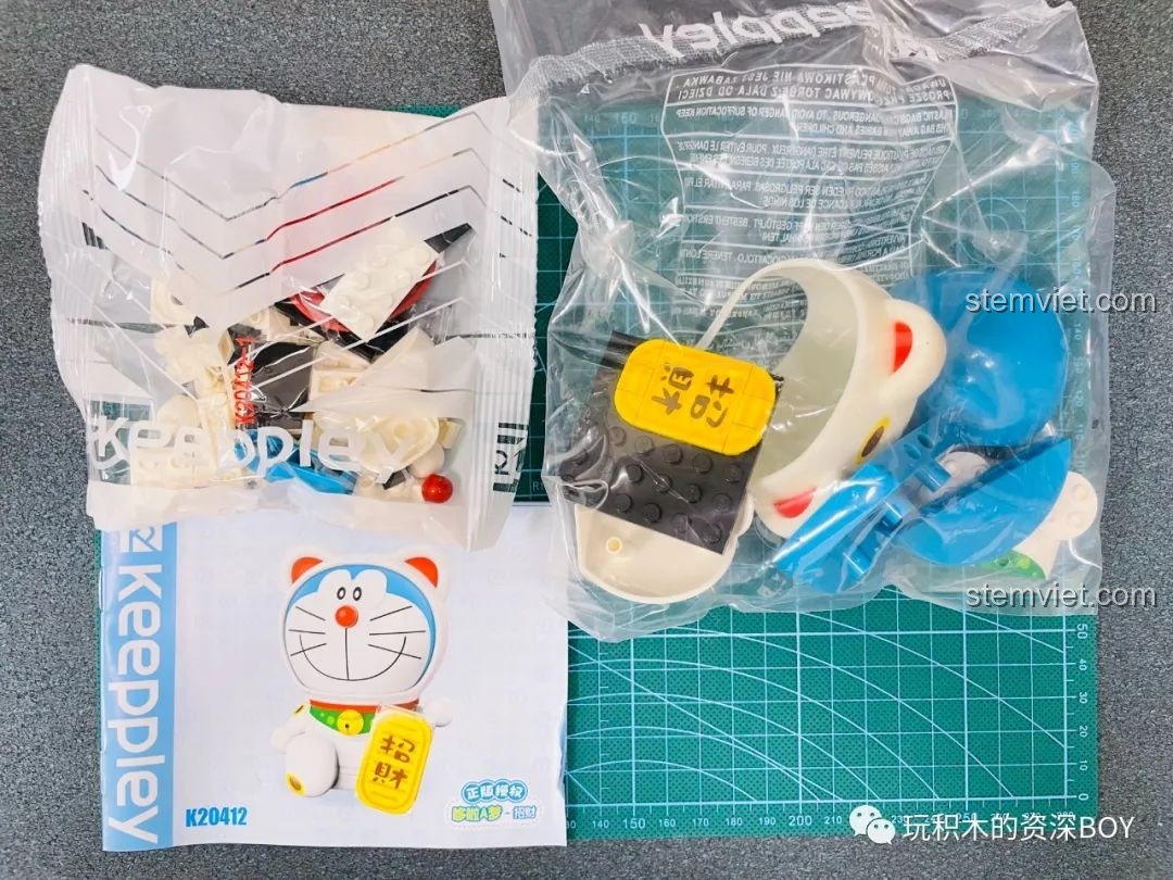 Sách hướng dẫn lắp ráp của bộ đồ chơi Keeppley Doraemon Mèo Thần Tài K20412 mở ra, hiển thị các bước lắp ráp chi tiết.