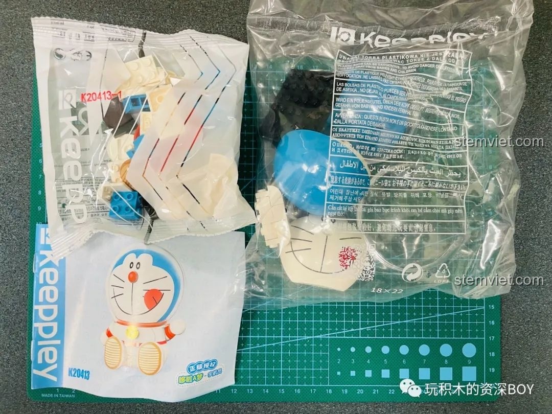 Các túi linh kiện và sách hướng dẫn của bộ đồ chơi lắp ráp Keeppley Doraemon phi hành gia K20413 được bày ra trên thảm cắt.