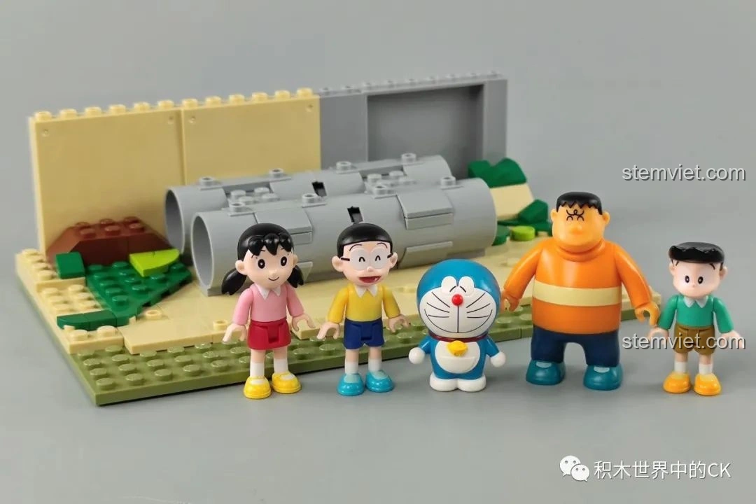 Năm minifigures Doraemon, Nobita, Shizuka, Suneo, Gian đứng trên phần đế lắp ghép ban đầu của bộ Keeppley K20409 Sân Chơi Ống Cống Doraemon.