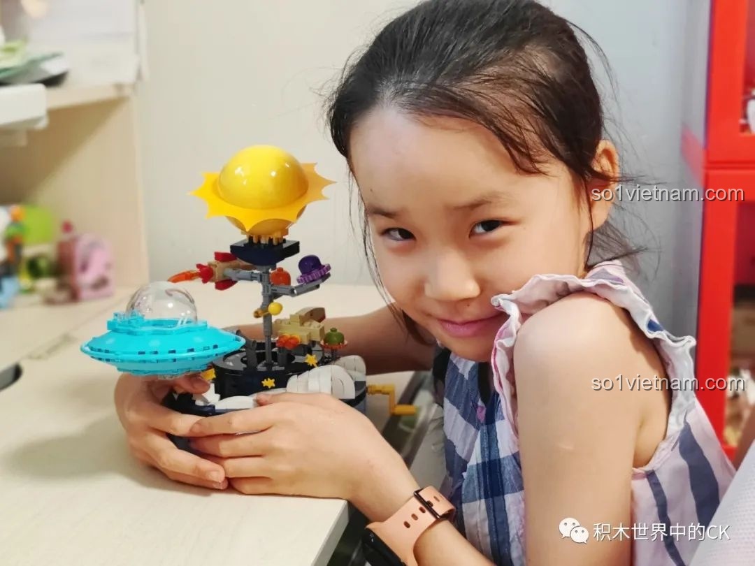 Bé gái đang dán sticker trang trí lên mô hình Keeppley K20421 Doraemon, thể hiện tính tương tác và sáng tạo của đồ chơi.