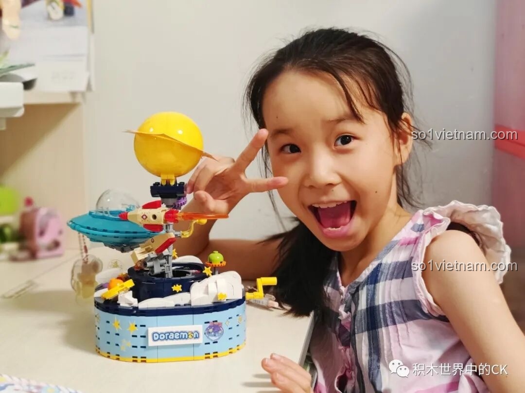 Bé gái đang chơi với mô hình Keeppley K20421 Doraemon, tương tác với cơ chế xoay và các chi tiết chuyển động của mô hình.