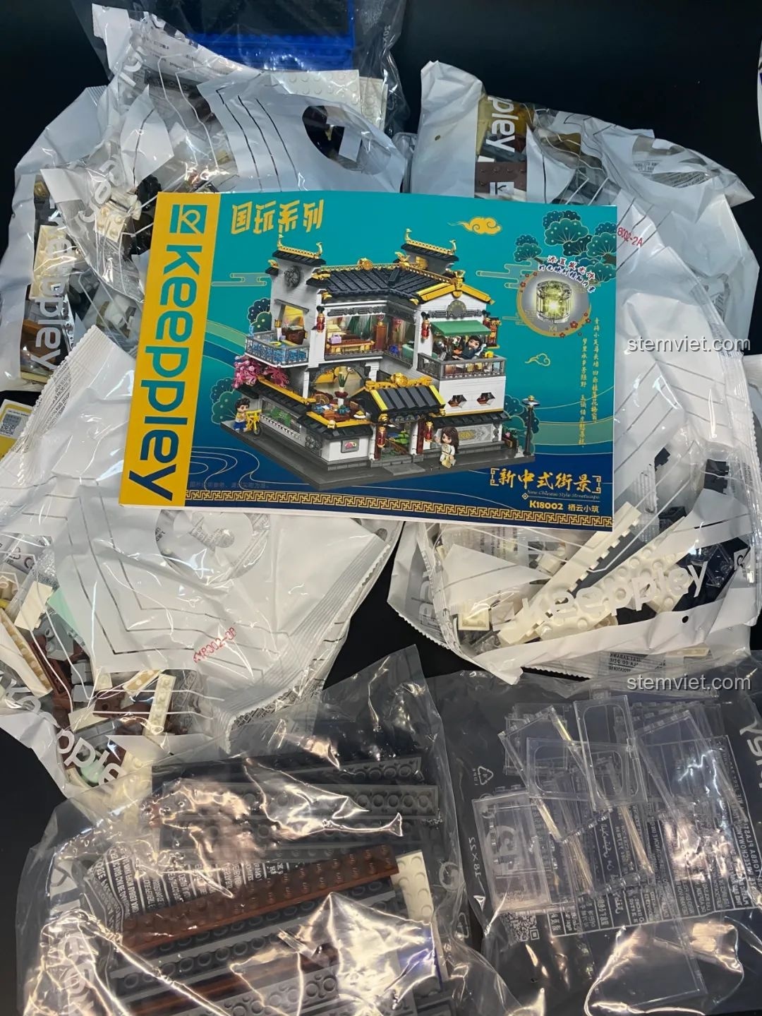 Các túi linh kiện được phân loại và sách hướng dẫn dày dặn của bộ lắp ghép Keeppley K18002 Phố Cổ Trung Hoa, sẵn sàng cho trải nghiệm lắp ráp.