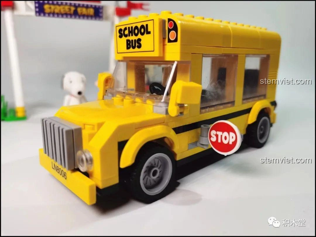 Mô hình hoàn chỉnh của bộ lắp ráp LiNooS LN8006 Snoopy Xe Buýt Trường Học và trạm dừng, được đặt trong khung ảnh.