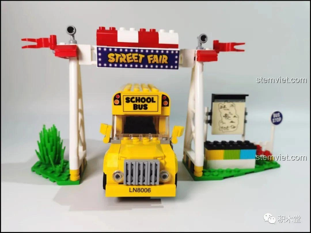 Mô hình xe buýt trường học LiNooS LN8006 Snoopy và cổng hội chợ Street Fair đã hoàn thiện, đặt cạnh nhau.